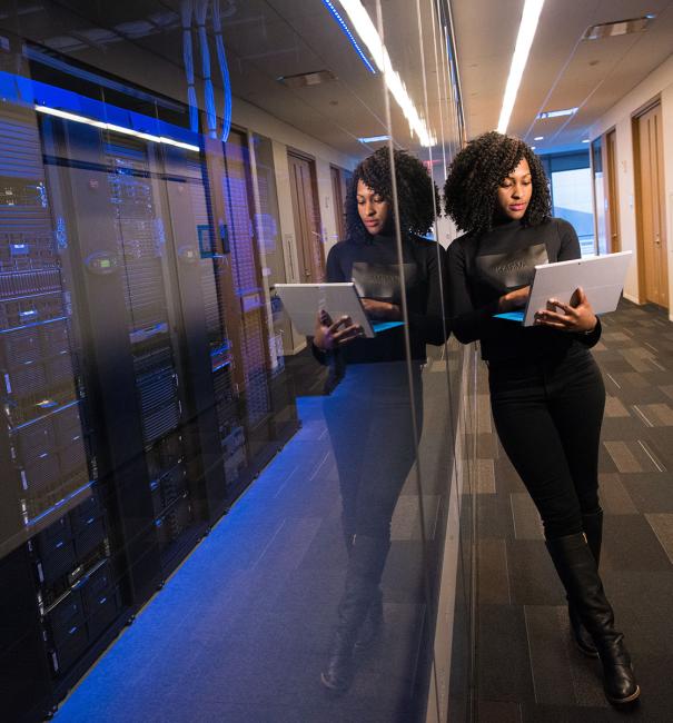 Engineer holding laptop next to server racks